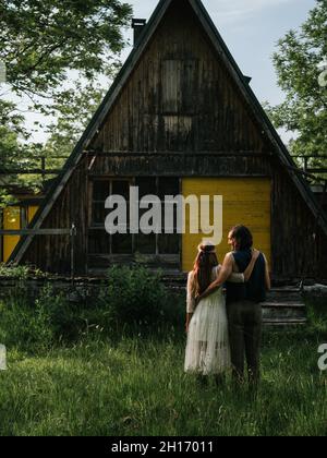 Vue arrière d'un couple attrayant embrassant devant une ancienne maison en bois Banque D'Images