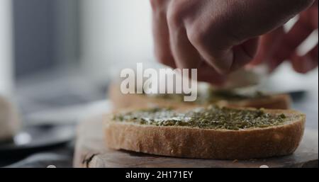 ajoutez de la mozzarella sur une tranche de ciabatta fraîche avec du pesto pour faire un sandwich gros plan, photo large Banque D'Images