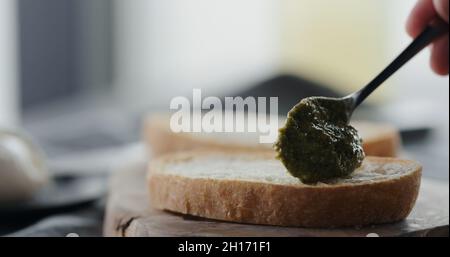 étalez le pesto sur une tranche de ciabatta fraîche pour faire un sandwich de gros plan, photo large Banque D'Images