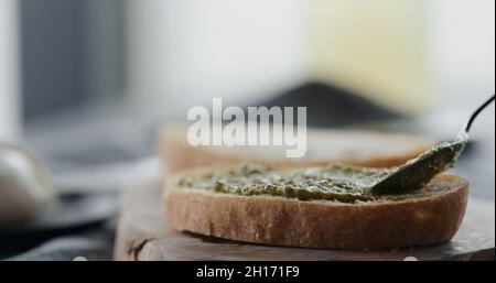 étalez le pesto sur une tranche de ciabatta fraîche pour faire un sandwich de gros plan, photo large Banque D'Images