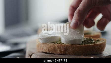 ajoutez de la mozzarella sur une tranche de ciabatta fraîche avec du pesto pour faire un sandwich gros plan, photo large Banque D'Images