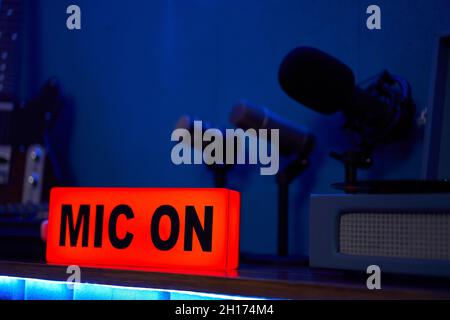 Microphones modernes sur trépied placés sur une table dans un studio sombre avec éclairage au néon avant l'enregistrement du podcast Banque D'Images