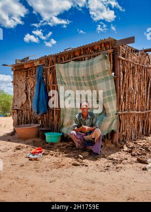 Ancien bushman en face de la cabane du Kalahari central, village de New Xade au Botswana Banque D'Images