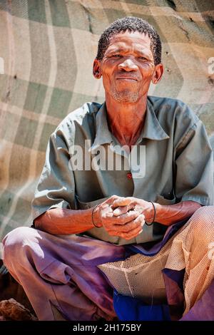 Un vieil homme de brousse du Kalahari central, du village de New Xade au Botswana, devant sa cabane Banque D'Images