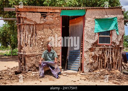 Un vieil homme de brousse du Kalahari central, du village de New Xade au Botswana, devant sa cabane Banque D'Images