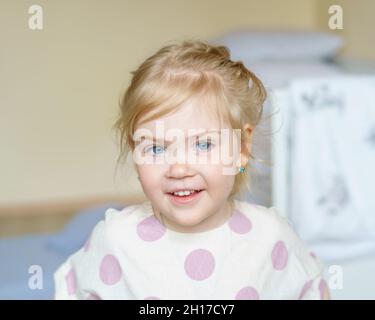 Adorable petite fille avec des yeux bleus et des cheveux dorés regardant l'appareil photo Banque D'Images