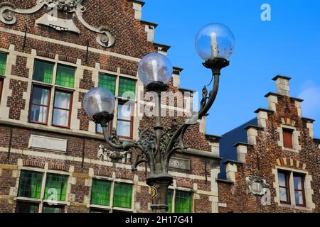 Gand, Belgique - octobre 9.2021: Gros plan de trois vieilles lampes de rue armées avec façade de maison de pignon étagée belge typique sur fond bleu ciel Banque D'Images