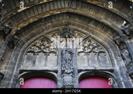 Gand, Belgique - octobre 9.2021: Détail de l'extérieur de l'église médiévale gothique entrée en pierre avec arche ronde, petits voussoirs, holdin de la figure sainte Banque D'Images