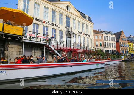 Gand, Belgique - octobre 9.2021: Vue sur la rivière avec le bateau touristique et le fond médiéval de bâtiment contre le ciel bleu Banque D'Images