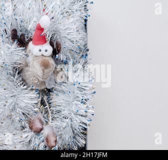 Un cerf jouet avec les yeux renflés se trouve dans la tinelle argentée.Décoration de Noël.Vue de dessus Banque D'Images