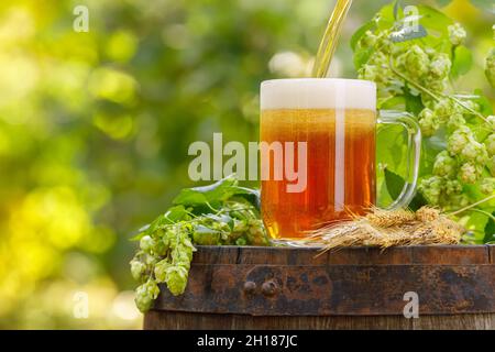 bière versant dans une tasse en verre sur un fût en bois Banque D'Images