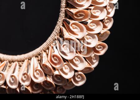 Collier fait à la main de coquillages en spirale se pose sur fond noir, produit artisanal traditionnel des îles de l'Asie du Sud-est Banque D'Images