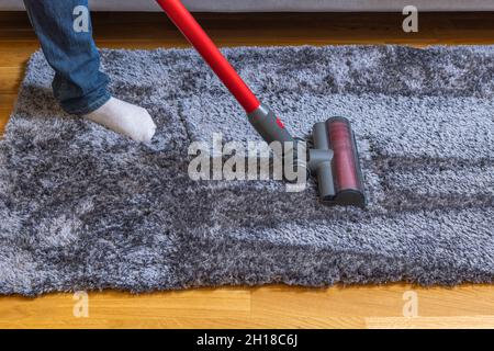 Vue rapprochée de l'homme passant l'aspirateur sur un tapis de parquet.Suède. Banque D'Images