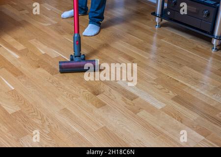 Vue rapprochée de l'homme passant l'aspirateur sur le parquet.Suède. Banque D'Images