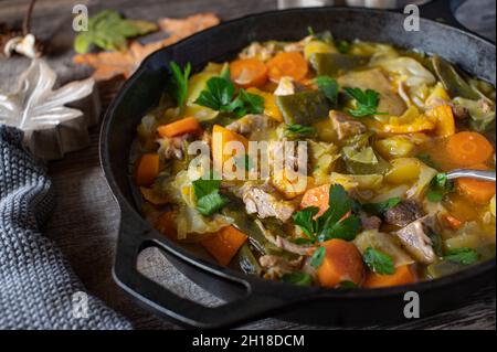 Ragoût avec de délicieux légumes d'automne et d'hiver comme la citrouille, les haricots verts, les carottes, le chou et la viande de porc.Servi sur fond de table en bois Banque D'Images