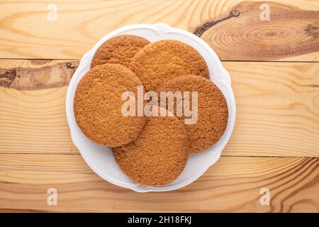 Plusieurs délicieux biscuits américains ronds sur une plaque blanche en céramique, gros plan, sur une table en bois, vue du dessus. Banque D'Images