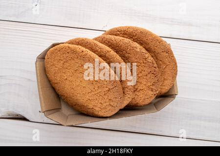 Plusieurs délicieux biscuits américains ronds dans une boîte en papier, gros plan, sur une table en bois, vue du dessus. Banque D'Images