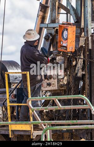 L'opérateur sur un engin de maintenance de puits exécutant les commandes de l'engin sur un puits de pétrole. Banque D'Images