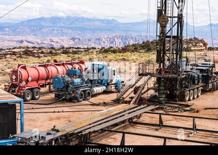 Un engin de reprise avec un camion-citerne et un camion-pompe acidilisant un puits de pétrole pour restaurer la production.Utah. Banque D'Images