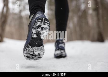 Hiver exercice fitness style de vie athlète marchant avec des chaussures de course sur la neige et la glace glissante ayant besoin de semelles d'adhérence sur les trottoirs glacés.Courez à l'extérieur Banque D'Images