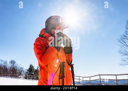 Sports d'hiver femme skieur soufflant son nez de course en ski sur la piste de ski de montagne en plein air.Asiatique athlète fille portant un casque et des gants, veste Banque D'Images