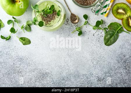 Ingrédients pour le smoothie vert, les microverts de pois d'épinards bio frais, la banane, le kiwi, la pomme et la graine de chia sur fond de béton gris clair. En bonne santé Banque D'Images
