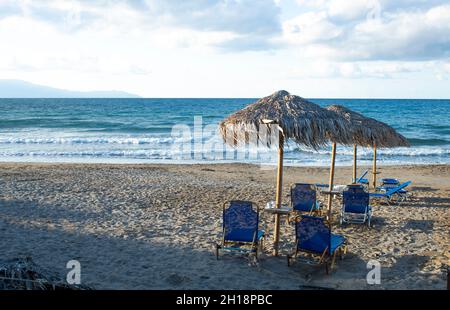 Bord de mer, Agia Marina, île de Crète, Grèce des chaises longues sur une plage de sable dans cette petite station grecque près de la Canée aspect paysage avec espace de copie Banque D'Images