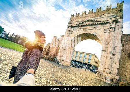 Homme suivant une femme bien-aimée en vacances d'automne - concept amusant avec les voyageurs dans la vieille ville de Rimini à Augustus Arch Banque D'Images