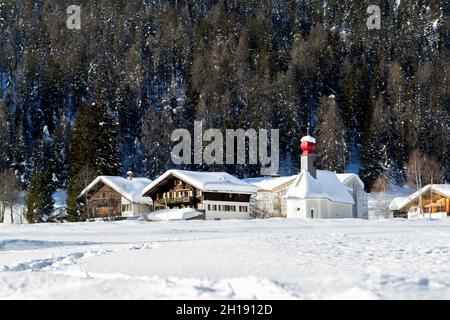 Maisons de village des Alpes suisses et une petite église avec un dôme rouge en hiver enneigé Banque D'Images