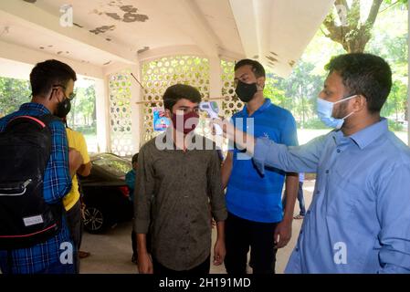 Dhaka, Bangladesh.17 octobre 2021.Un fonctionnaire vérifie la température corporelle d'un étudiant de l'Université de Dhaka alors qu'il arrive pour assister à un cours après un an et demi, a rouvert le maintien des directives Covid-19 et des protocoles de santé à Dhaka, au Bangladesh, le 17 octobre 2021.Credit: Mamunur Rashid/Alamy Live News Banque D'Images