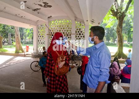 Dhaka, Bangladesh.17 octobre 2021.Un fonctionnaire vérifie la température corporelle d'un étudiant de l'Université de Dhaka alors qu'il arrive pour assister à un cours après un an et demi, a rouvert le maintien des directives Covid-19 et des protocoles de santé à Dhaka, au Bangladesh, le 17 octobre 2021.Credit: Mamunur Rashid/Alamy Live News Banque D'Images