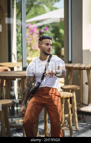 Un cliché vertical d'un athlète masculin en forme de caucasien tatoué assis sur un barhocker Banque D'Images
