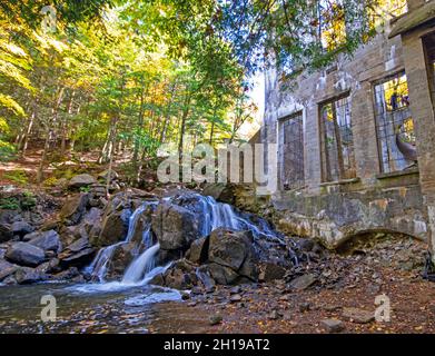 Cascade en automne à côté des ruines d'un ancien laboratoire dans les bois Banque D'Images