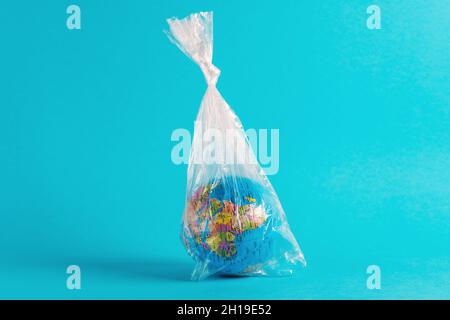 Globe terrestre dans un sac en plastique sur fond bleu.Concept écologique minimal. Banque D'Images