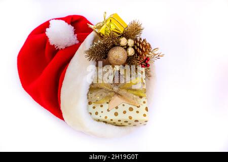 Un chapeau de Père Noël doux apporte un cadeau brillant pour un Noël doré et brillant. Banque D'Images