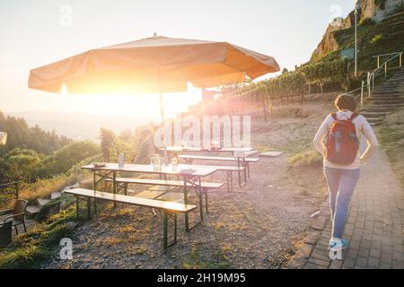 Vue arrière de la femme marchant au coucher du soleil vers le château de Schauenburg à Oberkirch, Bade-Wurtemberg Allemagne Banque D'Images