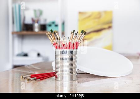 Un contenant en métal avec un jeu de pinceaux pour peindre dans un atelier d'art. Banque D'Images