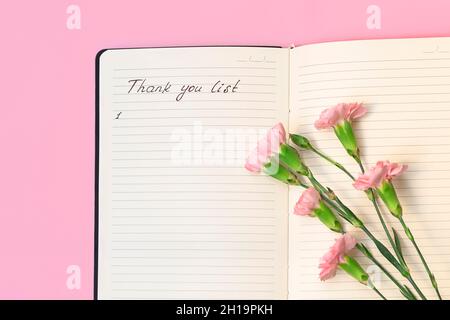 Au-dessus de la vue des fleurs sur papier ouvert bloc-notes avec des mots manuscrits liste de remerciements.Concept de journal de gratitude Banque D'Images