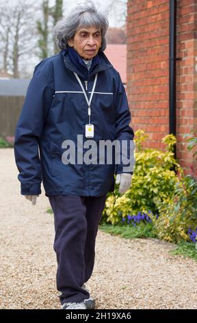 Vieille femme indienne portant des vêtements d'hiver et pendentif d'alarme de sécurité personnelle, marchant à l'extérieur, Royaume-Uni Banque D'Images
