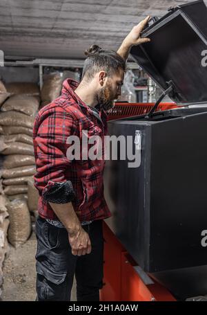 L'homme regardant dans une chaudière sur combustible solide dans la chambre avec des granulés. Banque D'Images