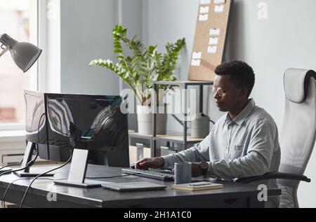 Portrait d'un homme afro-américain concentré utilisant un ordinateur tout en étant assis au bureau, concept de développeur de logiciels, espace de copie Banque D'Images