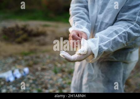 Le concept d'enquête sur le crime est à portée de main d'un médecin légiste inconnu qui met des gants en caoutchouc sur les lieux du crime pour recueillir des preuves Banque D'Images