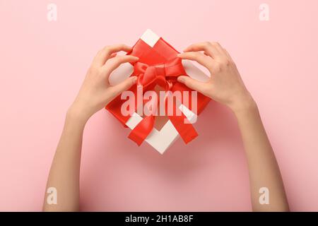 Femme nouant un noeud sur une boîte cadeau sur fond de couleur Banque D'Images