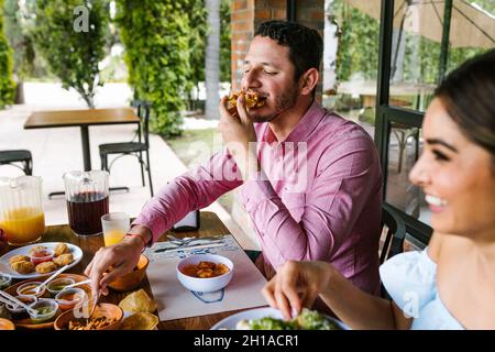 Jeune latino-américain mangeant des tacos mexicains sur une terrasse de restaurant au Mexique en Amérique latine, se sentant heureux lors d'une journée d'été Banque D'Images