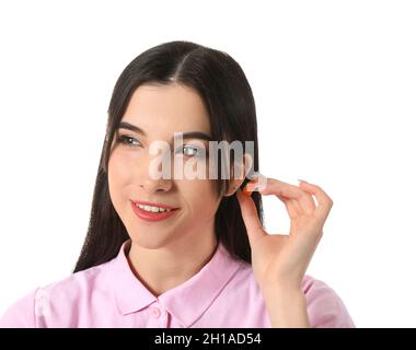 Jolie jeune femme mettant un bouchon d'oreille orange sur fond blanc Banque D'Images