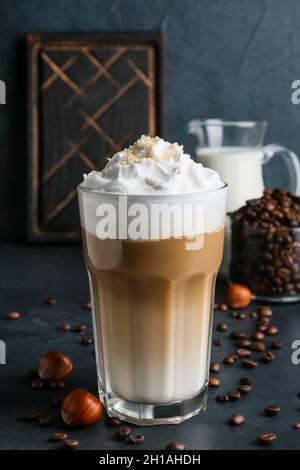 Verre de Latte savoureux avec noix et grains de café sur fond noir Banque D'Images