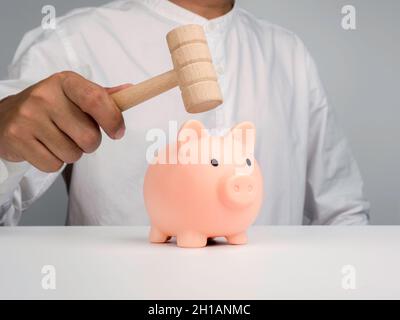 Pink piggy Bank et homme d'affaires main tient un marteau en bois pour frapper pour obtenir l'argent sur fond blanc. Banque D'Images