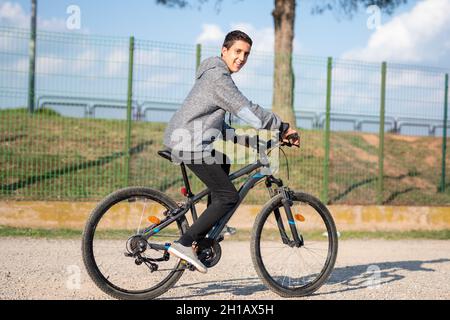 adolescent latin avec cheveux foncés et pantalon noir à vélo Banque D'Images