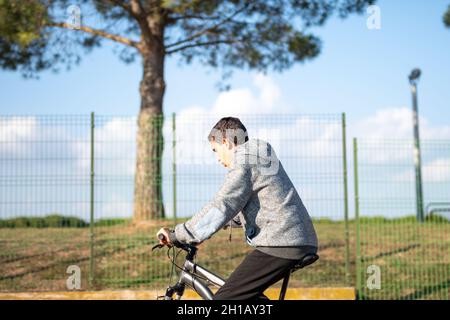 adolescent latin avec cheveux foncés et pantalon noir à vélo Banque D'Images