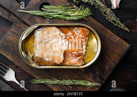Saumon sauvage de l'Alaska ensemble de poisson fumé en conserve, sur planche à découper en bois, sur fond de table en bois sombre avec herbes et ingrédients, vue du dessus plat Banque D'Images
